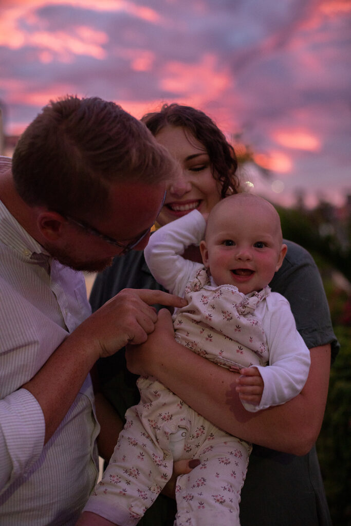 husband and wife holding their baby as the Mexico sun sets