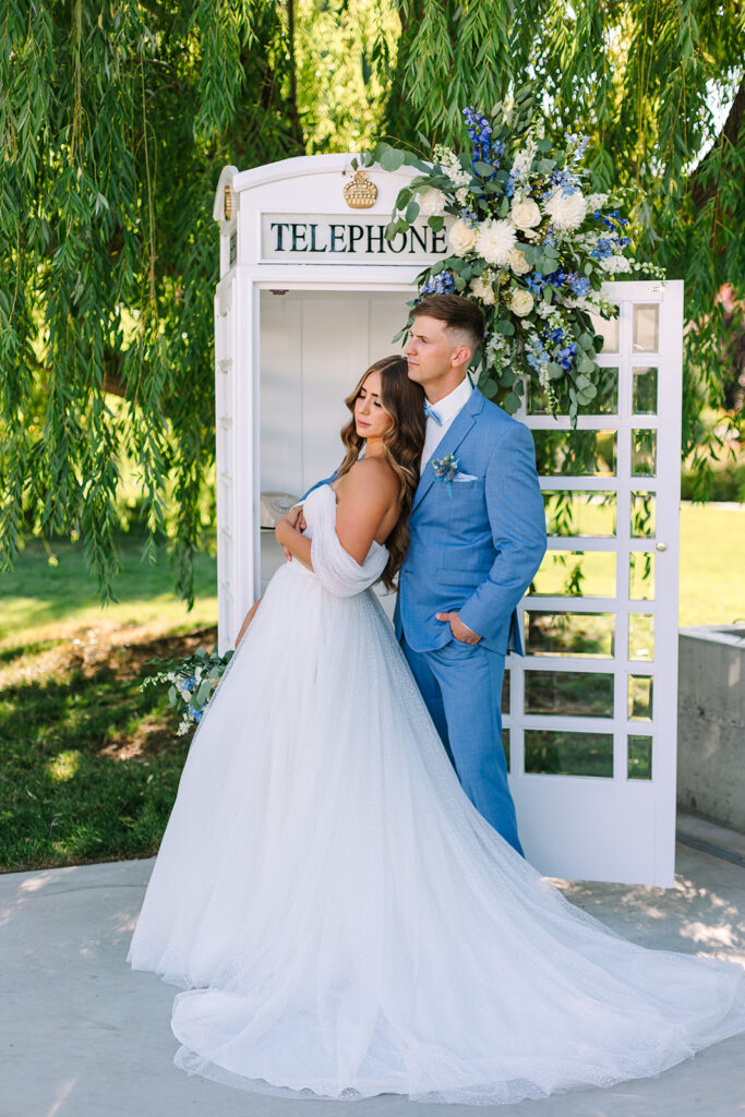 Couple poses in front of a white telephone booth at a tri-cities wedding venue